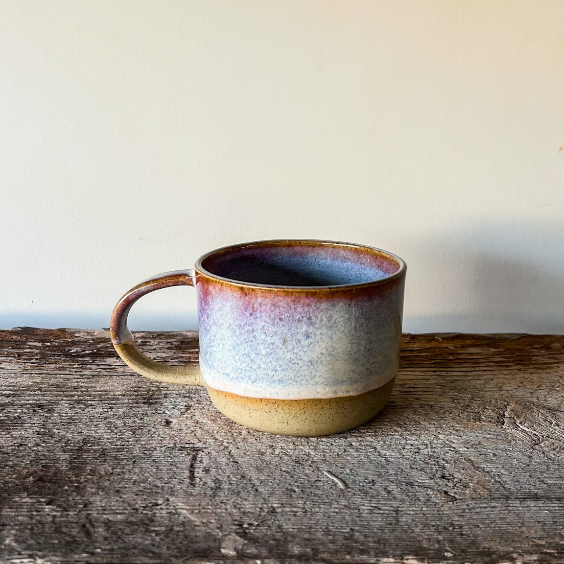 Ceramic mug with a multicolored glaze on a wooden surface