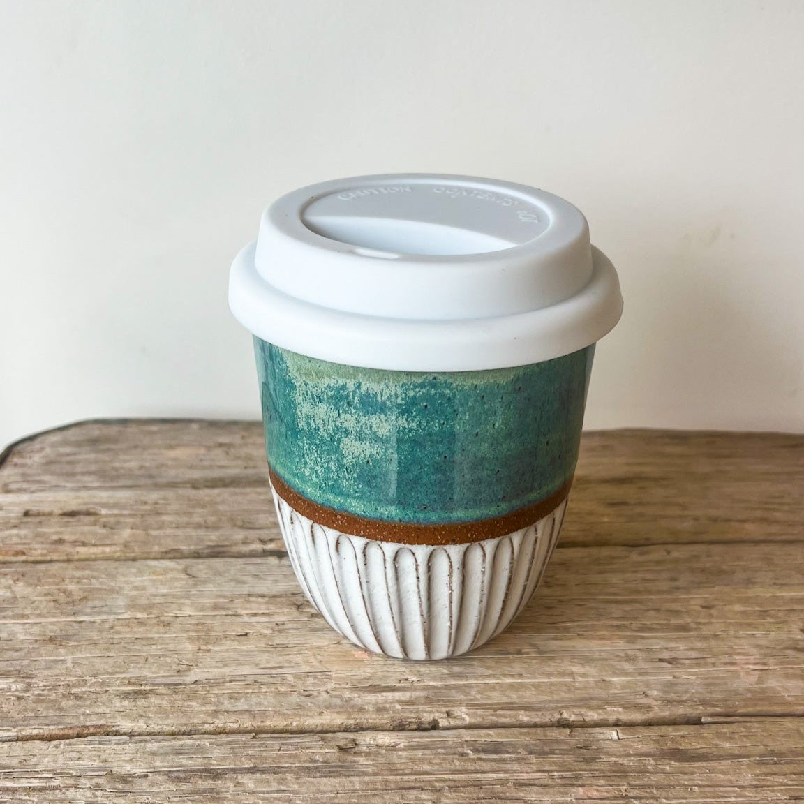 Ceramic coffee cup with a green and brown design on a wooden surface