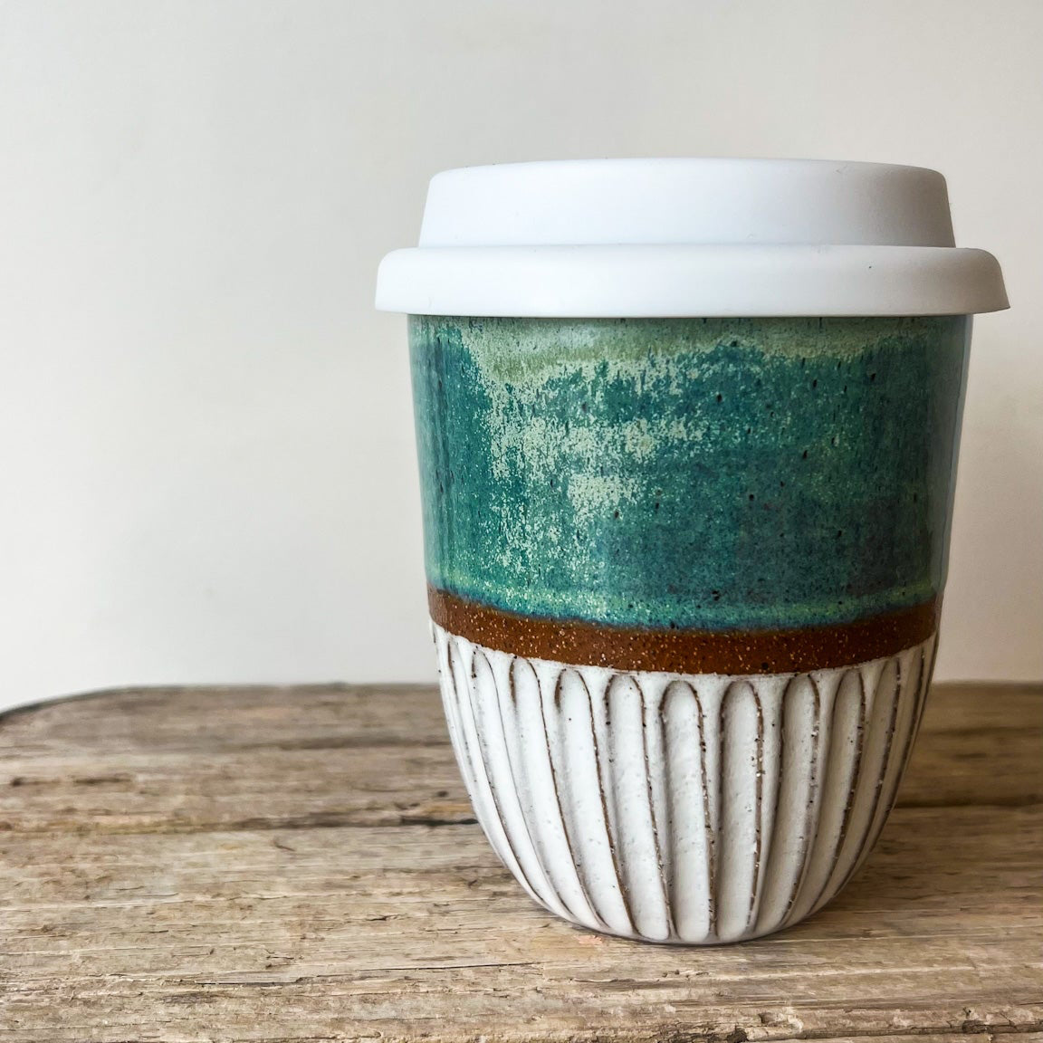 Ceramic coffee cup with a green and brown design on a wooden surface