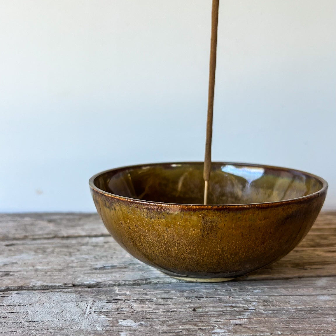 Brown ceramic bowl on a wooden surface with a white background