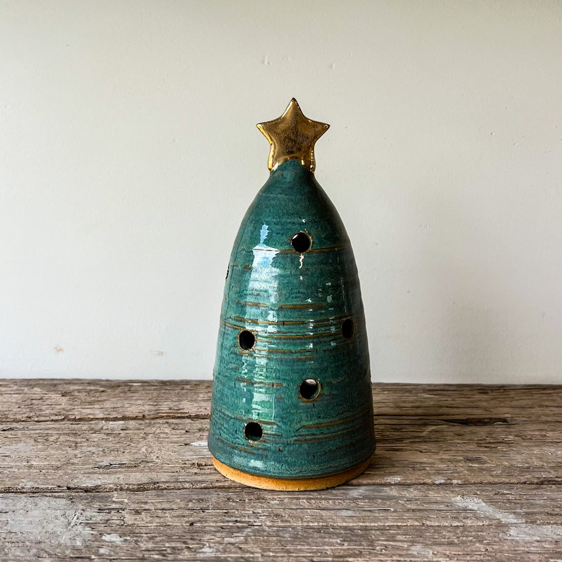 Green ceramic Christmas tree with a gold star on a wooden surface