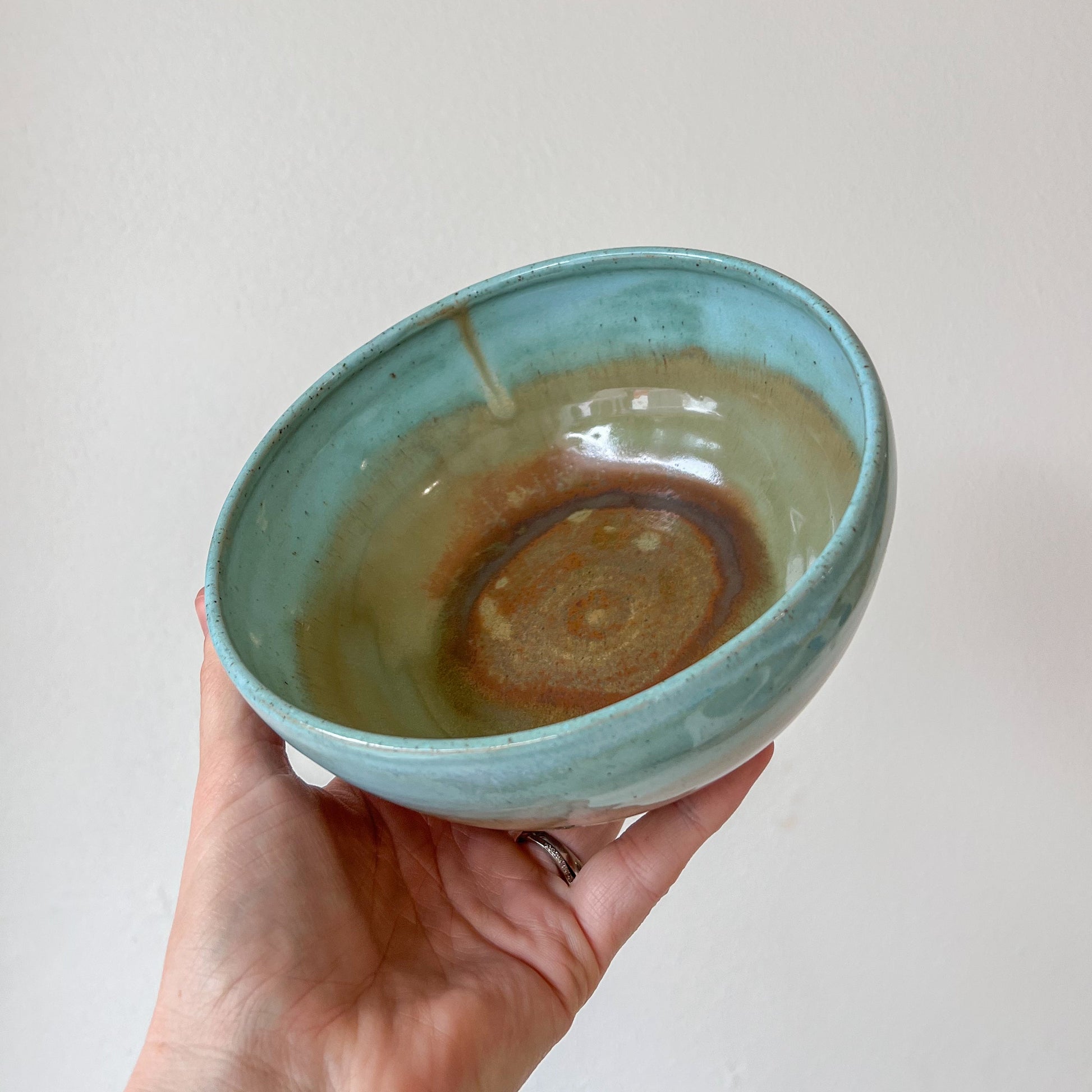 Hand holding a ceramic bowl with a textured surface against a plain background