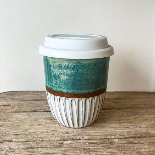 Ceramic coffee cup with a green and brown design on a wooden surface