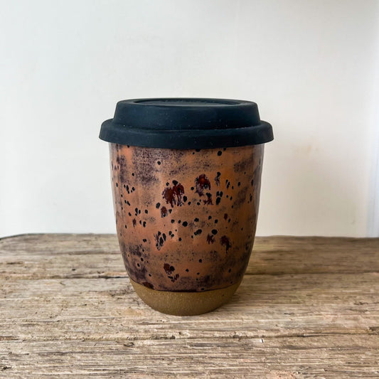 Ceramic cup with black lid on a wooden surface