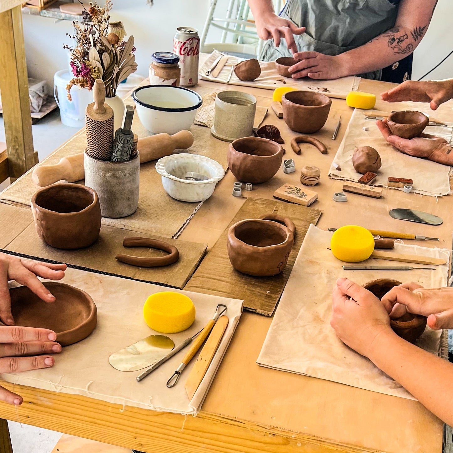 People working with clay on a pottery wheel in a workshop.