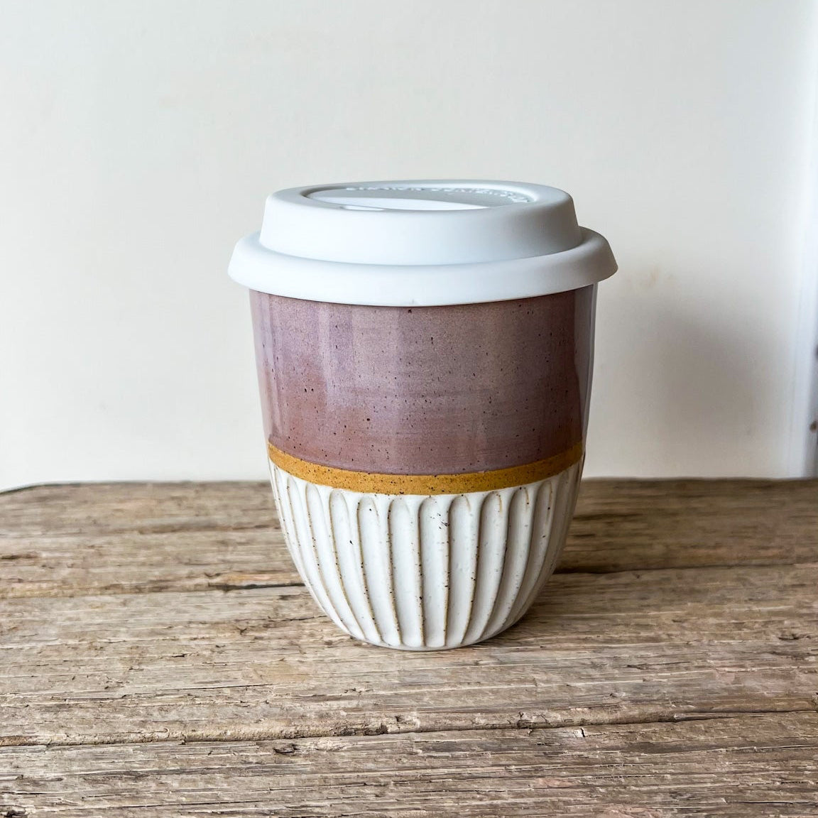 Ceramic coffee cup with a white lid.