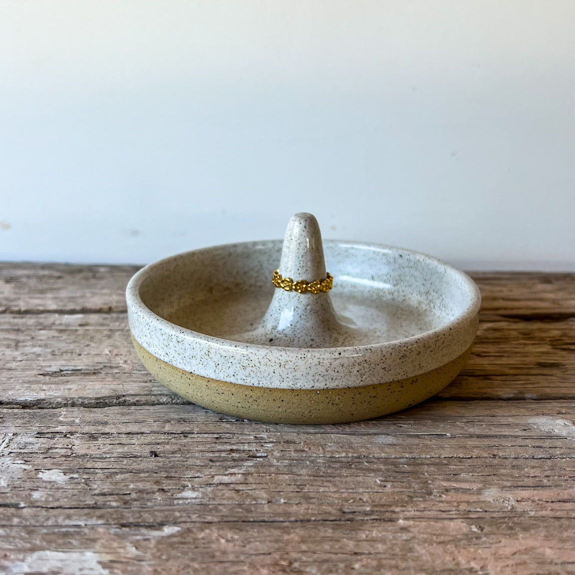Small ceramic ring dish on a wooden surface with a white background
