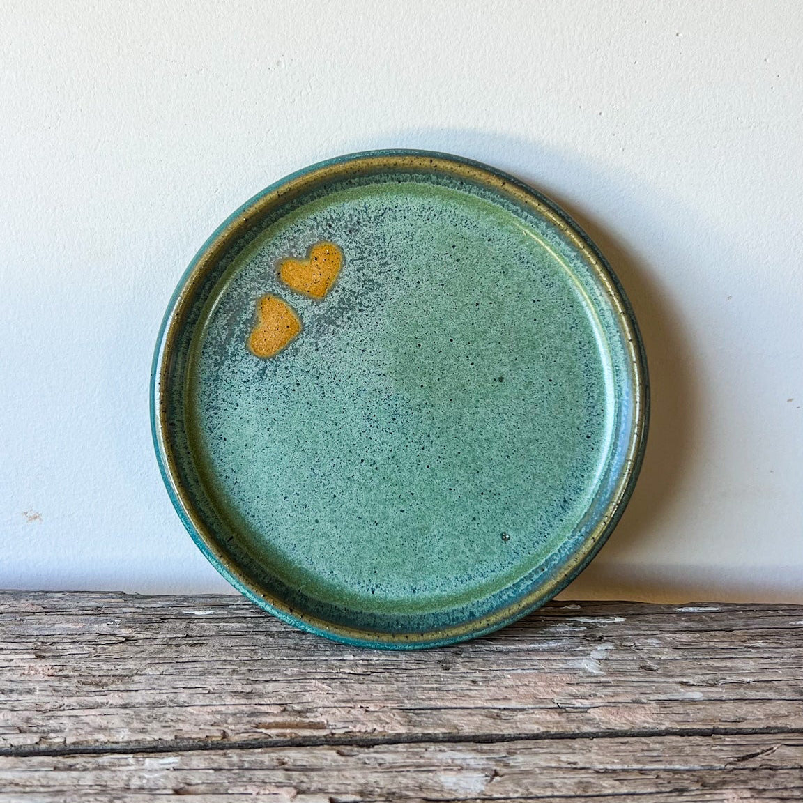 Green ceramic plate with heart designs on a wooden surface