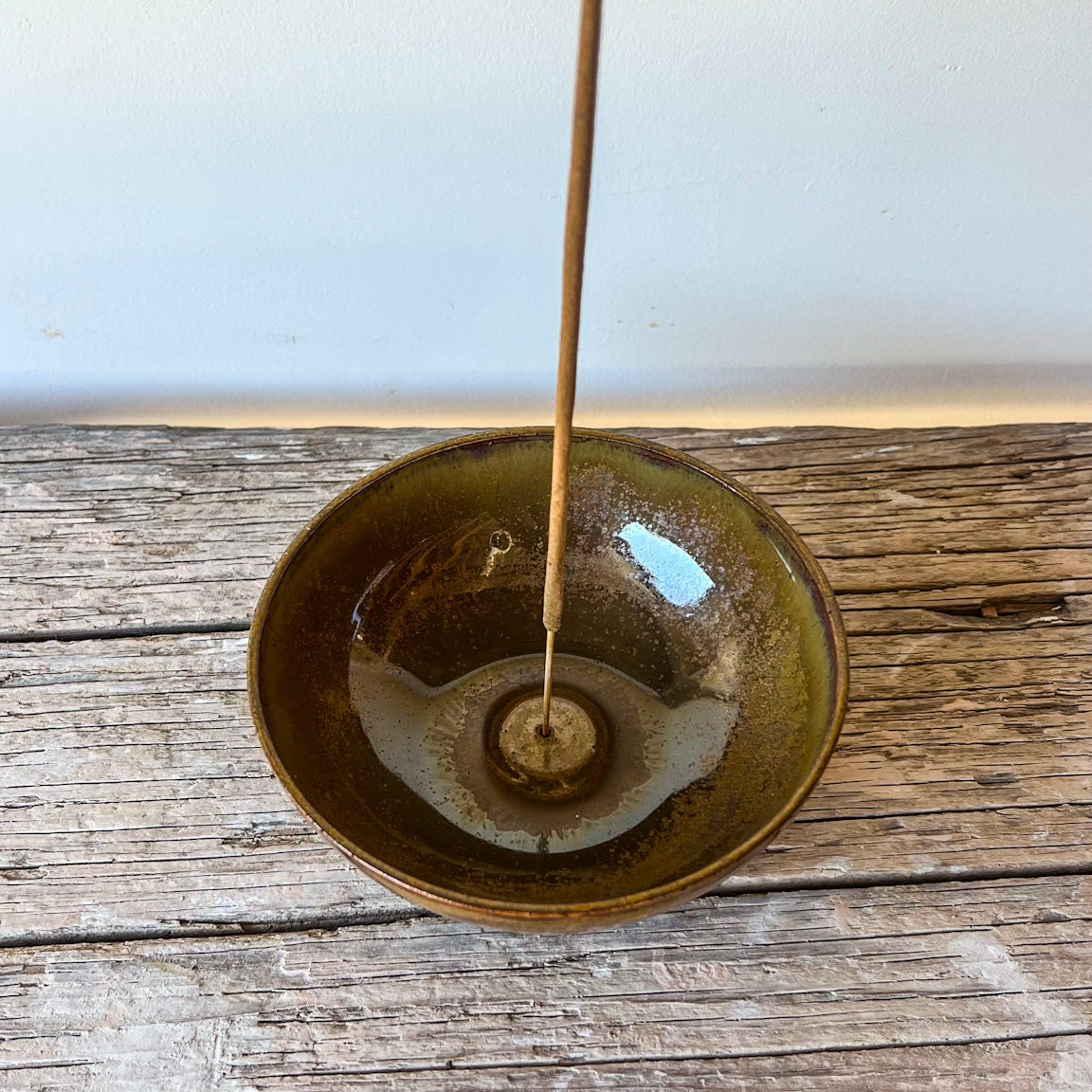 Incense stick in a ceramic holder on a wooden surface