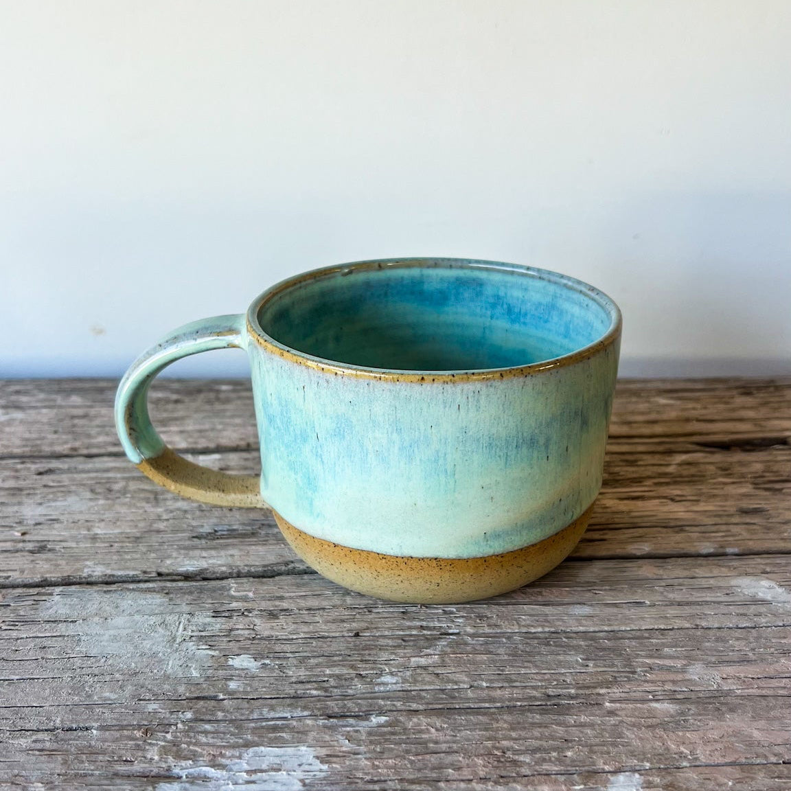 Ceramic mug with blue glaze on a wooden surface