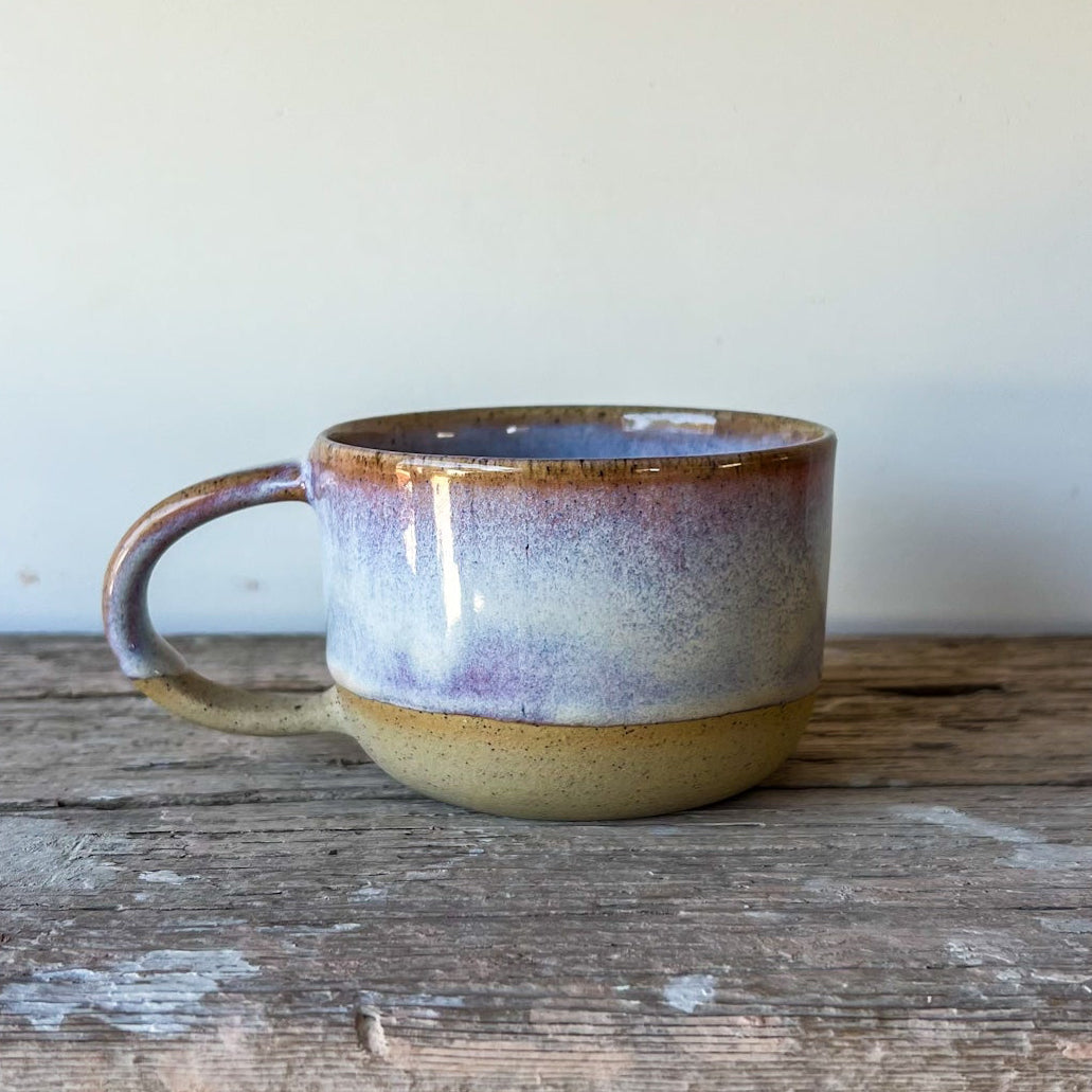 Ceramic mug with a purple rim on a wooden surface