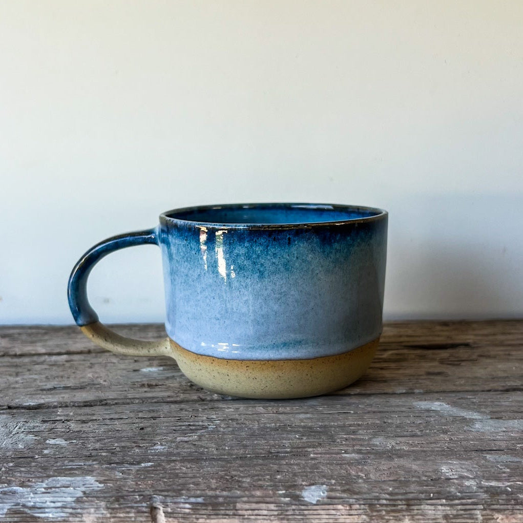Blue ceramic mug on a wooden surface with a plain background