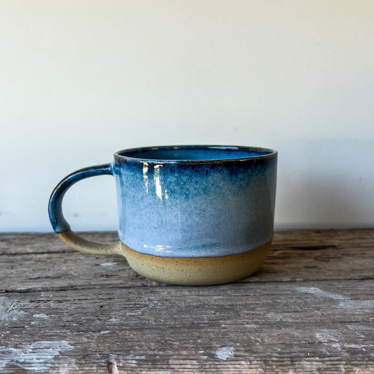 Blue ceramic mug on a wooden surface with a plain background