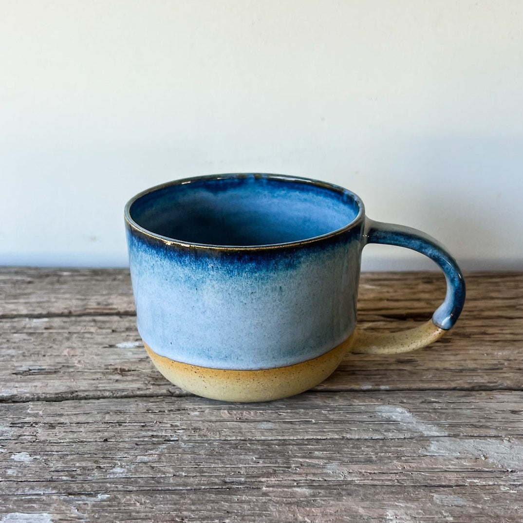 Blue ceramic mug on a wooden surface with a white background