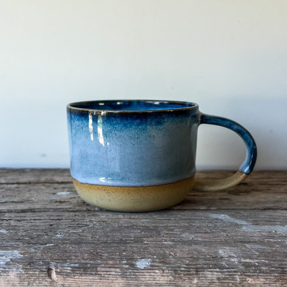 Blue ceramic mug on a wooden surface with a plain background