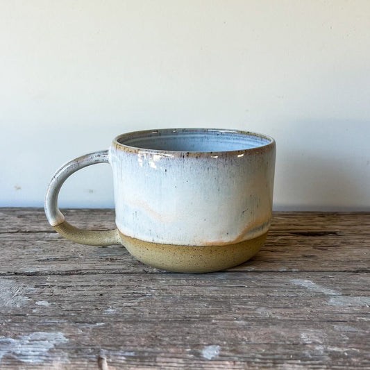 Ceramic mug on a wooden surface with a plain background