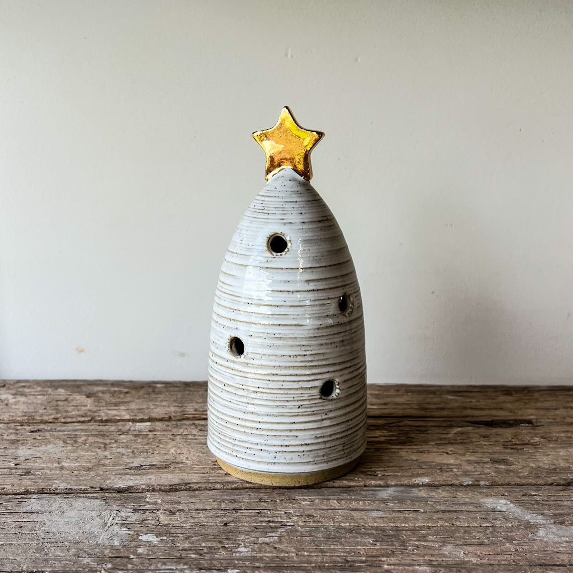 Ceramic Christmas tree with a star on top, placed on a wooden surface.