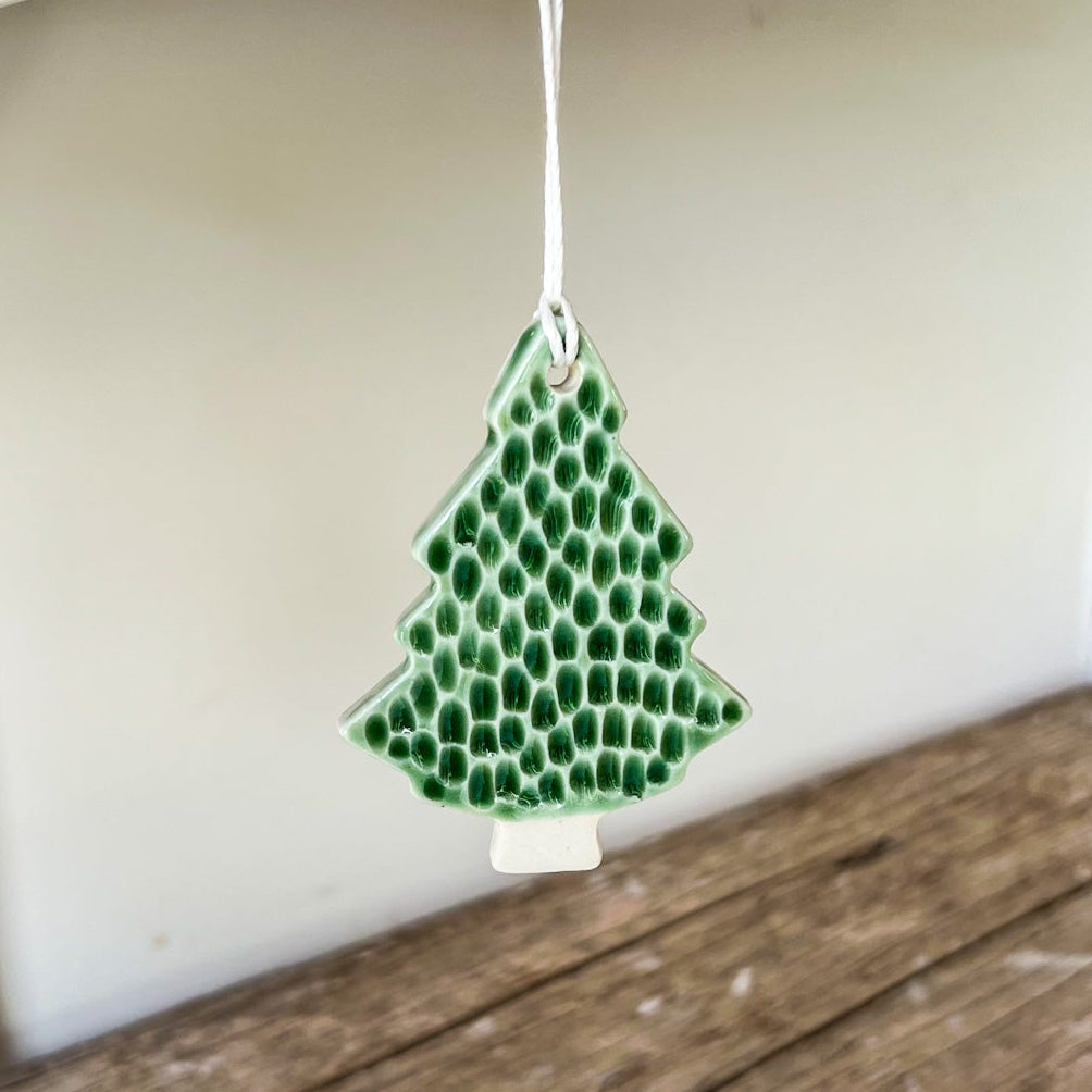 Green honeycomb-shaped ornament hanging on a wooden shelf.
